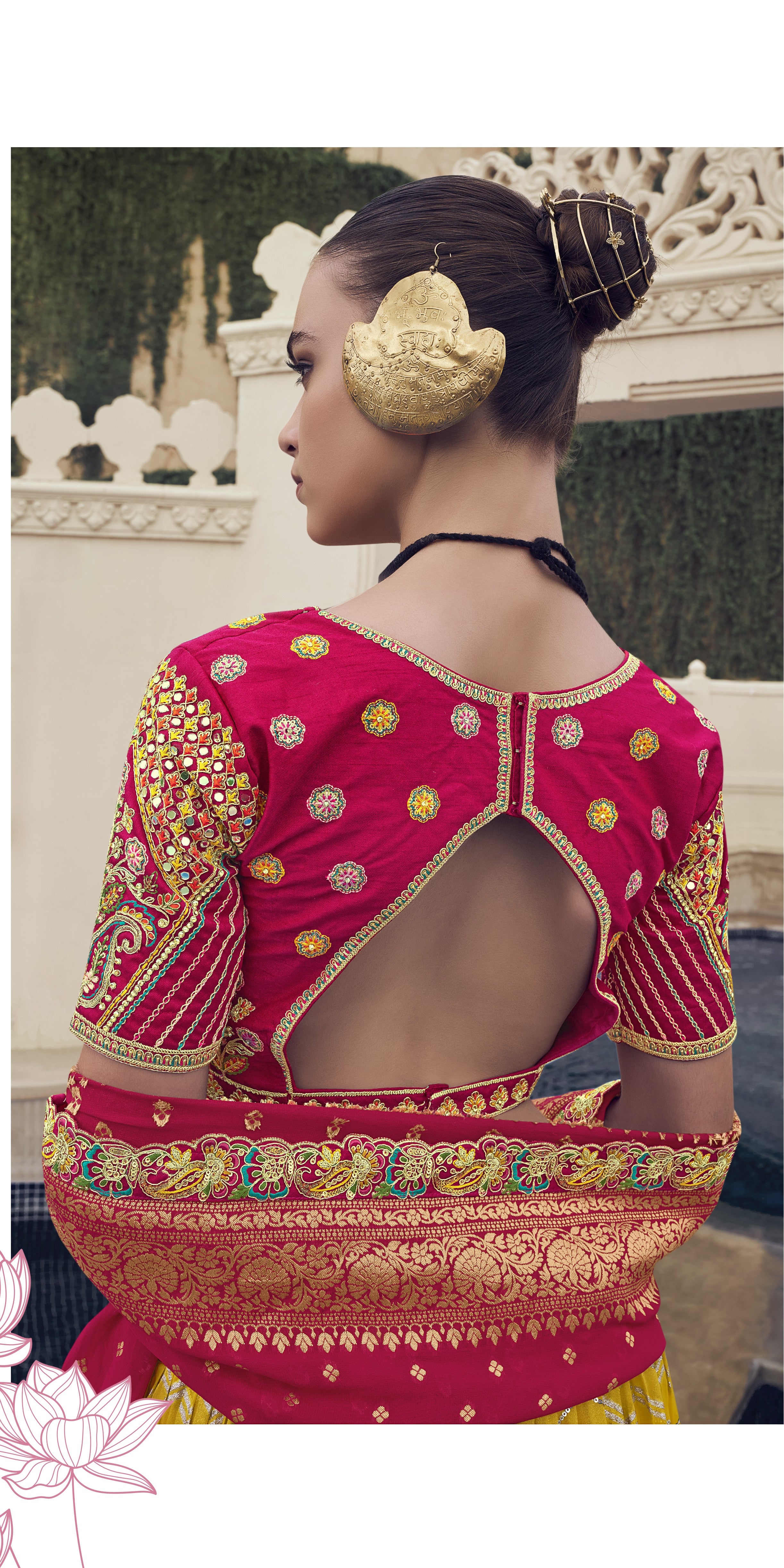 Woman in a traditional yellow and red Lehenga standing in front of an ornate building.