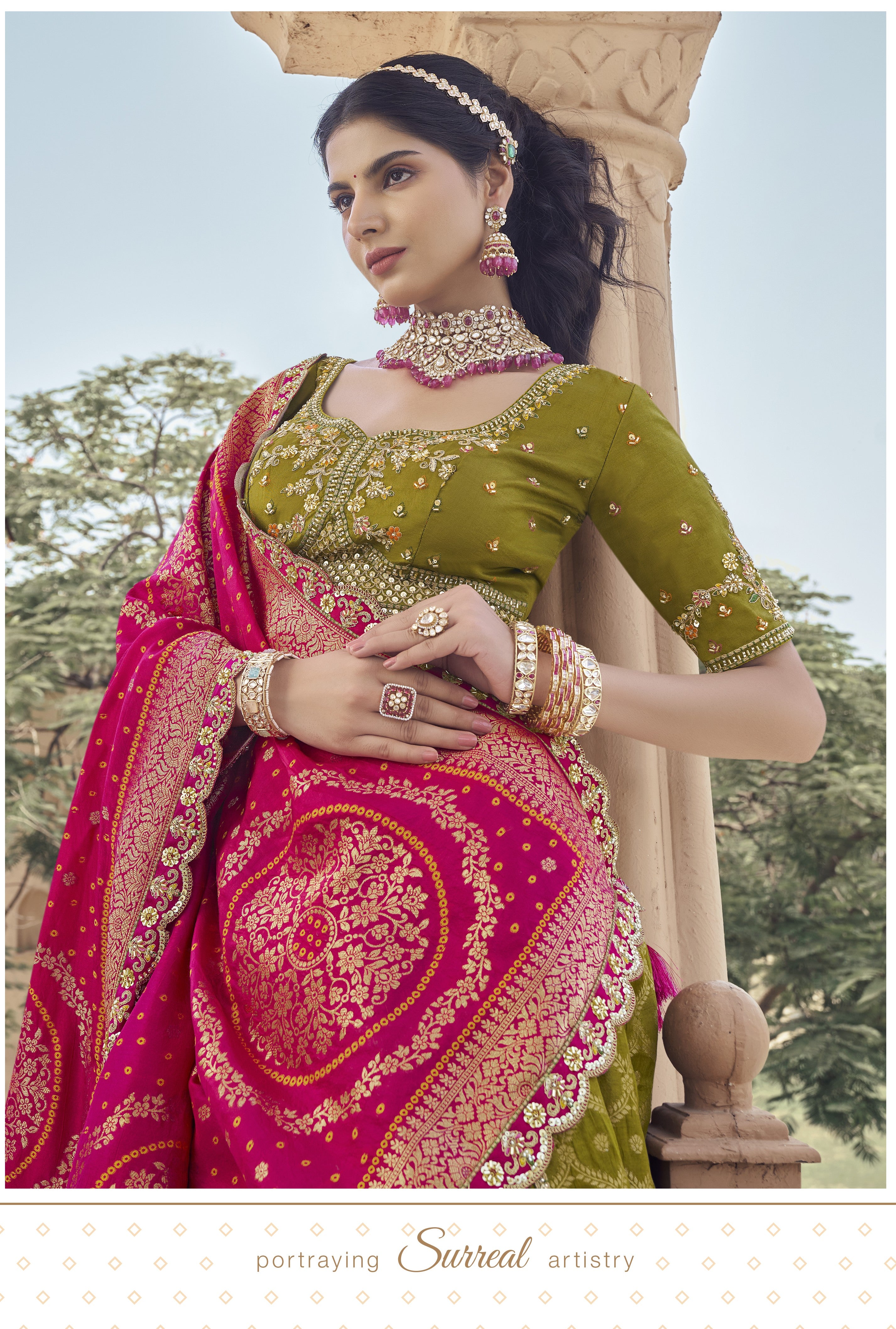 Woman in a green and pink Lehenga standing in front of an ornate archway.