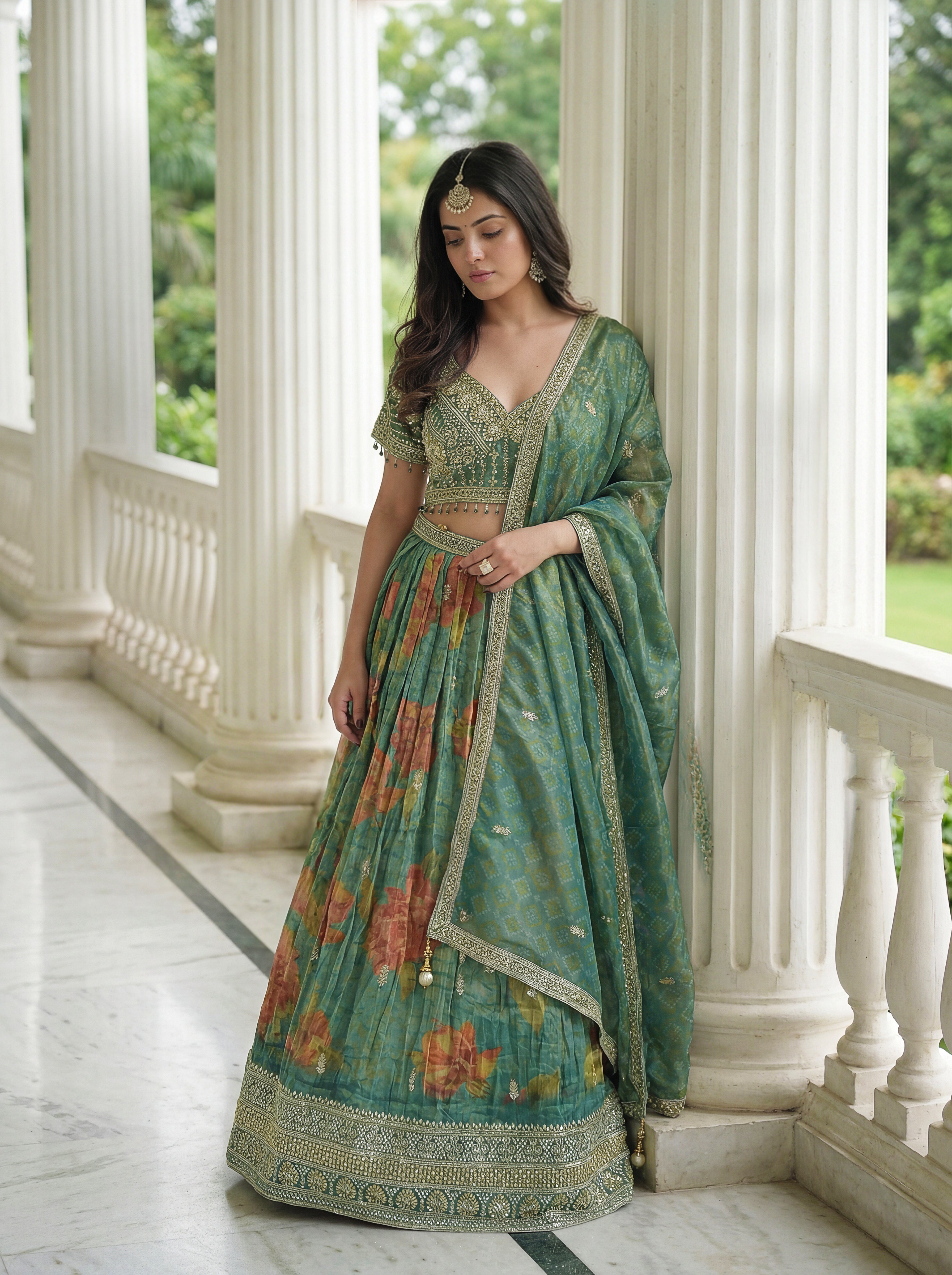 Woman in a green floral lehenga standing in a classical building setting